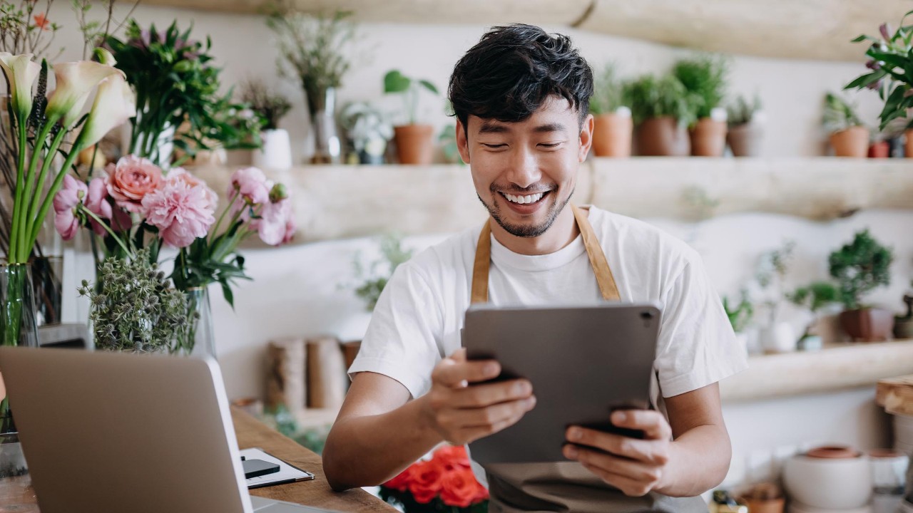 Businessman wearing stylish suit talking on mobile phone, holding laptop standing on the street. Successful business