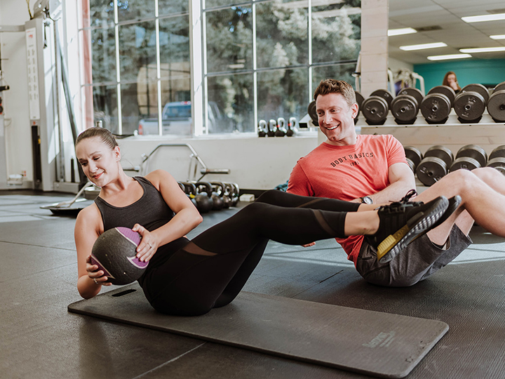 Woman and man dong a core workout with medicine balls  inside a gym