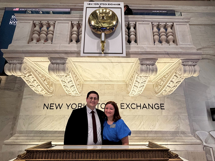 Colby Haupt and his wife standing in front of the New York Stock Exchange bell